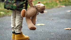 子供がぬいぐるみを片手に持って立ち尽くす