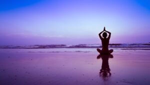 海辺に女性があぐらで座る瞑想のような写真