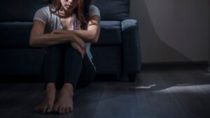 女性が体育座り　一人部屋